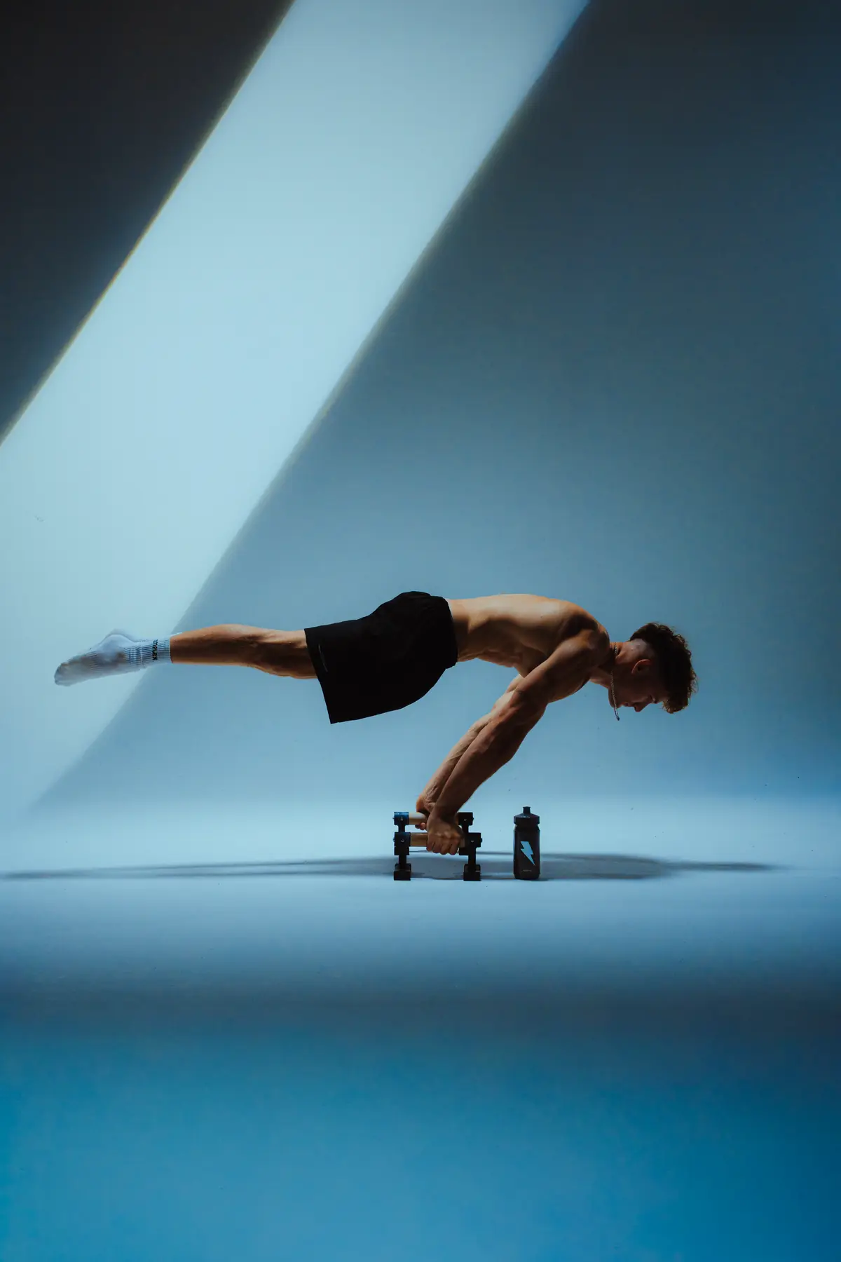 Tomáš Pospíšil v planche na paralelkách v modrém studiovém světle